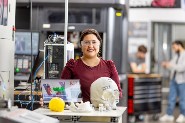 a woman with brown hair stands in a prosthetics lab