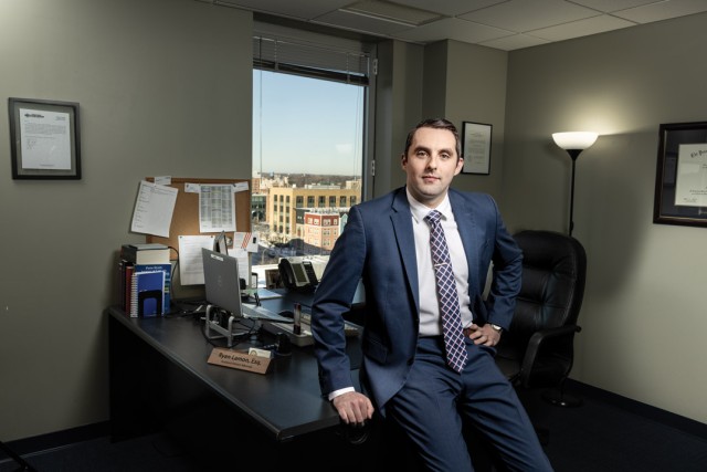 a man sits against a desk in a blue suit 