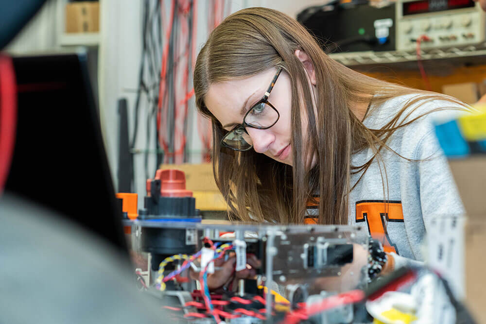 Girl bending over electronics and working