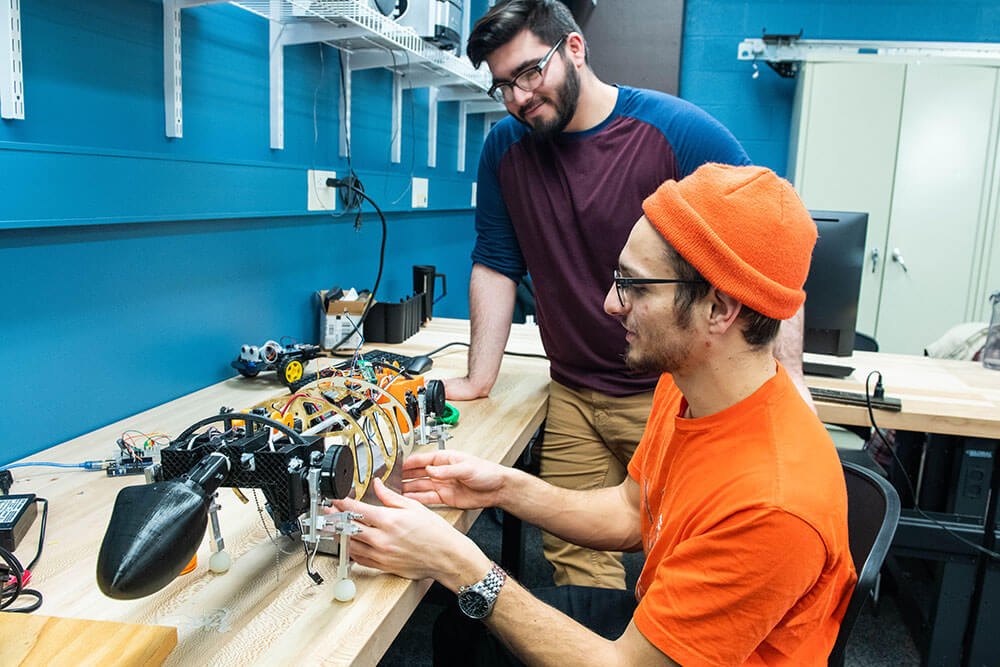 Two students working on a skeleton of the robofish