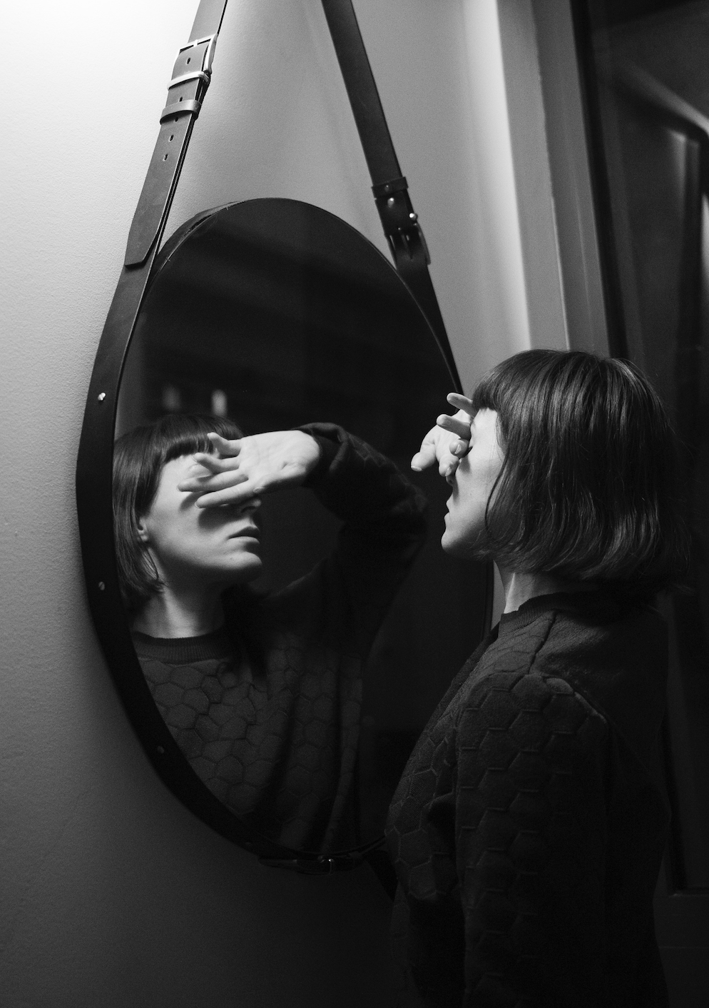 black and white photo of woman looking in mirror