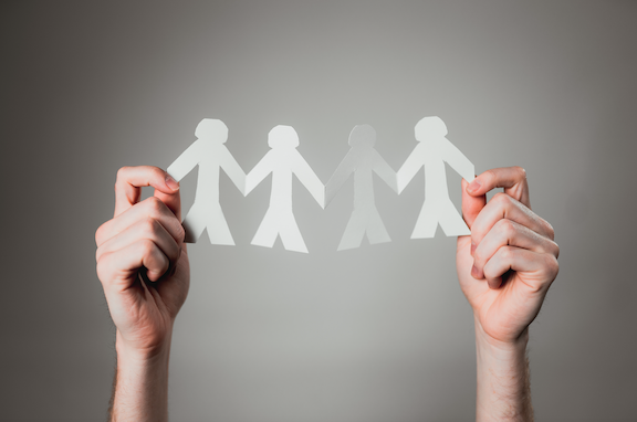 two hands holding paper cut out people in line