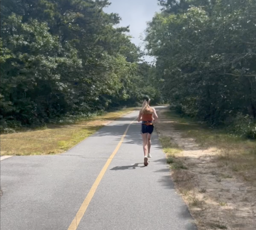 Picture of young woman running down road, as seen from behind her