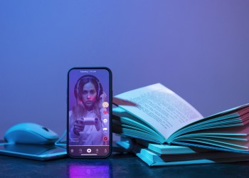 books alongside mobile phone featuring woman's face
