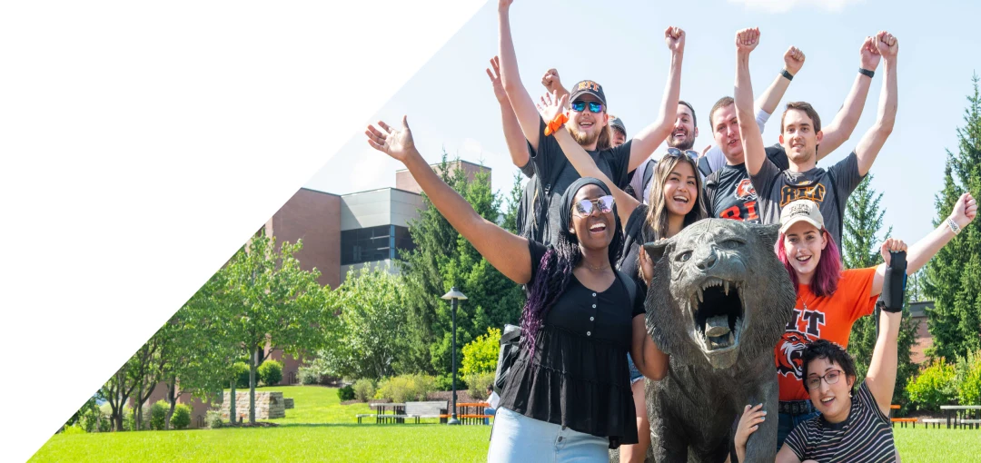 People posing with tiger statue with their arms in the air