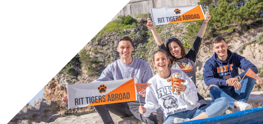 People sitting on a hillside with RIT banners