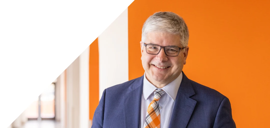 Bill Sanders in front of a solid orange wall