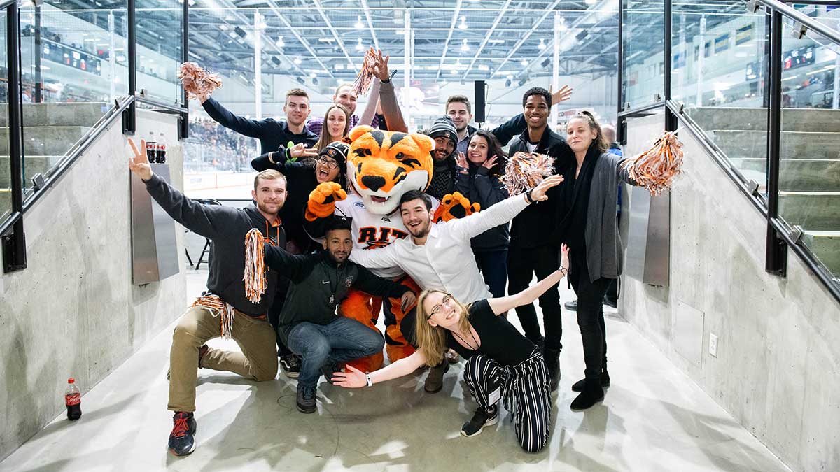 Students posing for a photograph in a hockey arena.
