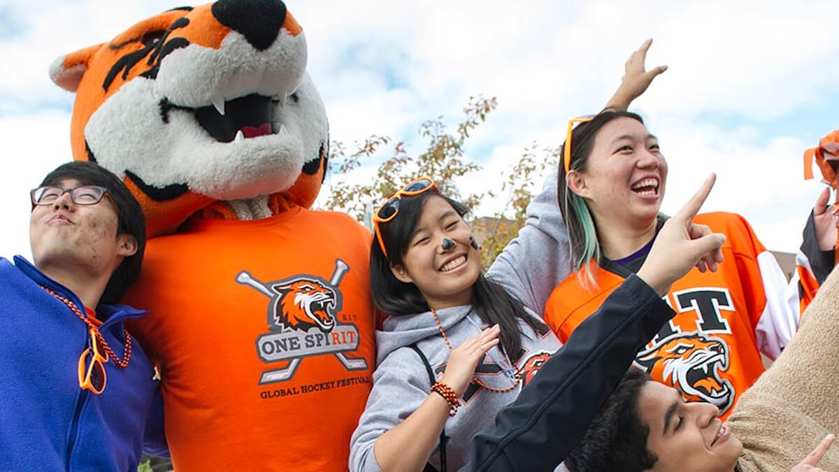 RITchie celebrating with students with arms in the air