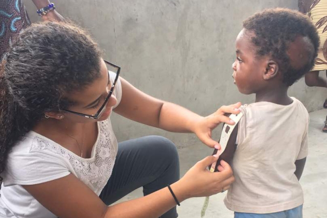 Woman measures arm of child with strip to determine anemia.