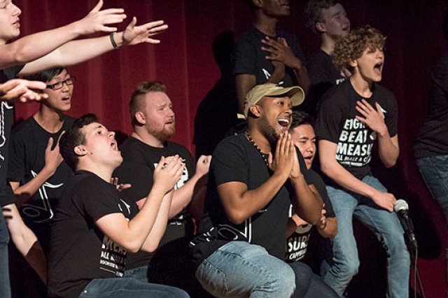 members of an a cappella group singing on one knee.