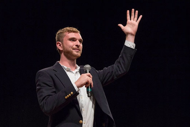 Bobby Moakley with a microphone in hand raising up his other arm.