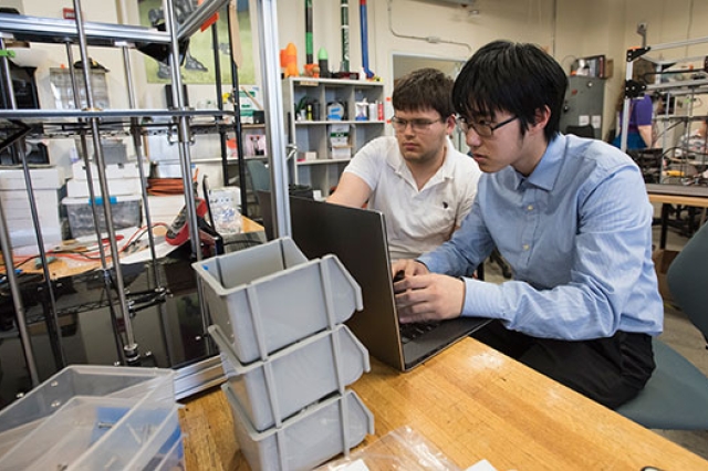 two students working on a laptop in maker space.