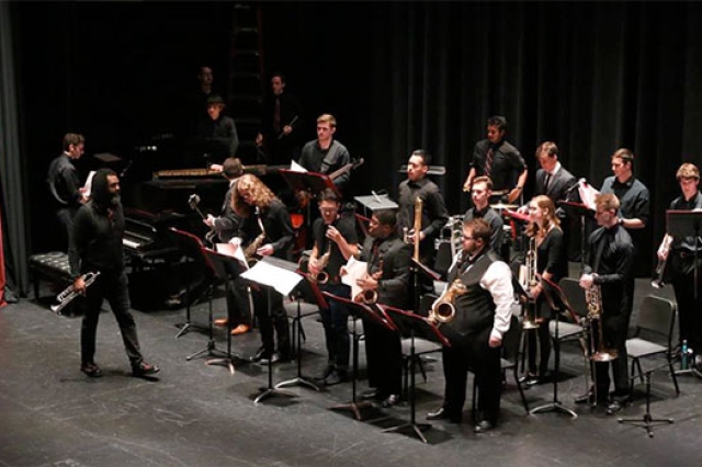 Musical ensemble dressed on state with instruments in hand.