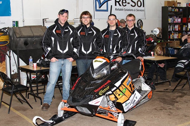 People posing by Snowmobile