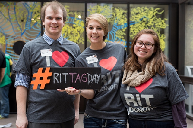 Three people Posing with "RIT Tag Day" sign