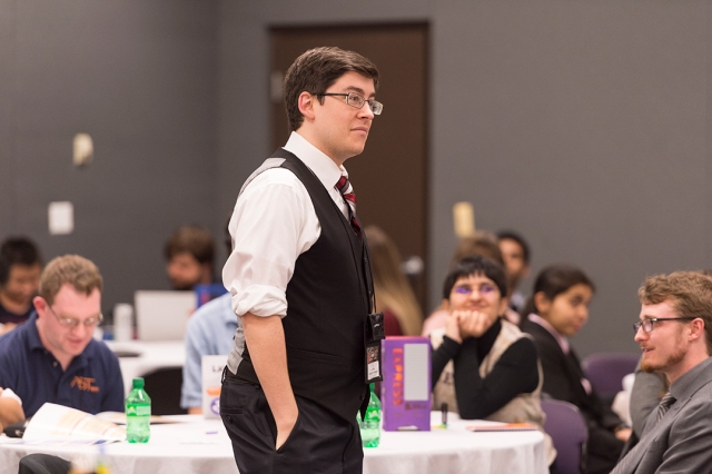 Male student with glasses dressed in suit.