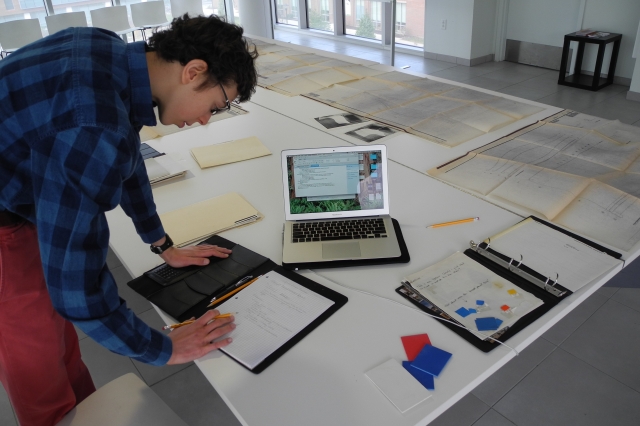 Anglemyer leaning over a desk in the Vignelli Center doing work