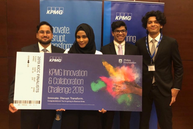 Four RIT Dubai students stand holding giant check