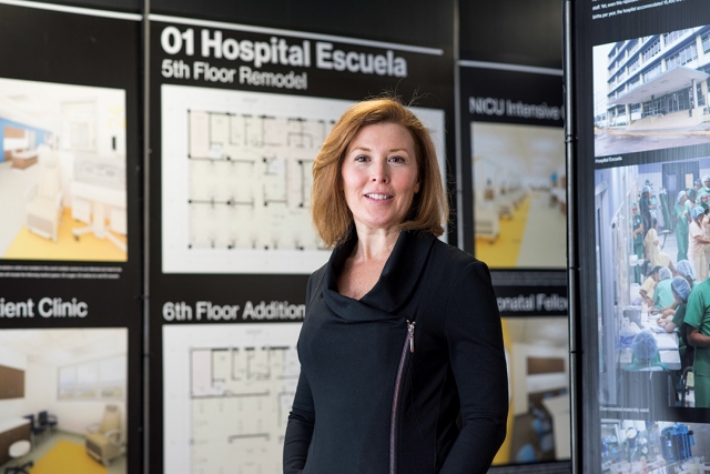 Woman stands in front of display of hospital floor plans