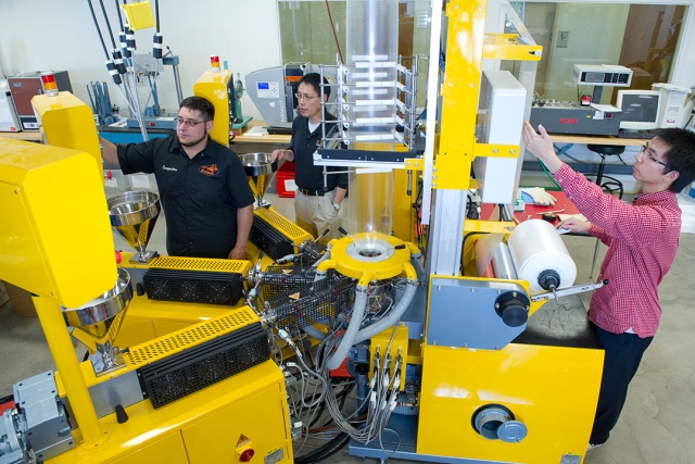 Students work with large, yellow machinery.