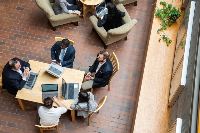 Overhead view of students working on laptops at table.