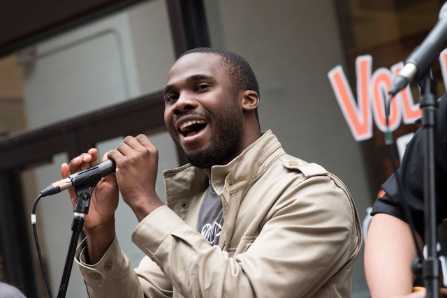 Adesola “Dewé” Adedewe sings into a microphone.