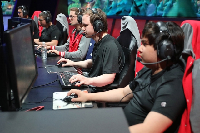 students wearing headset sitting a table with computers.