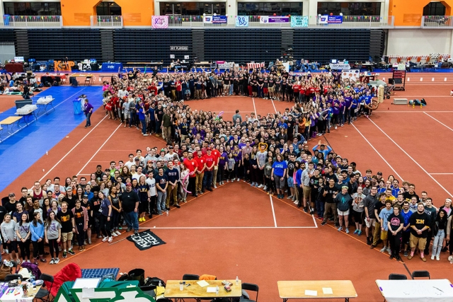crowd of people standing in the shape of a ribbon.