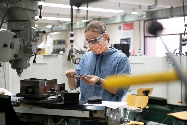 student wearing mask and safety glasses calibrating calipers. 