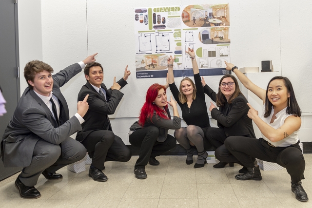 A group of smiling students point at their design concept that won the 2020 Hyperspace design challenge.
