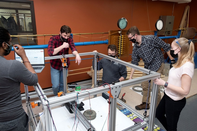 five students observing a 3D concrete printer.
