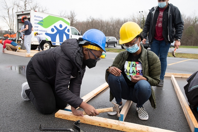two students building a wall frame for a house.