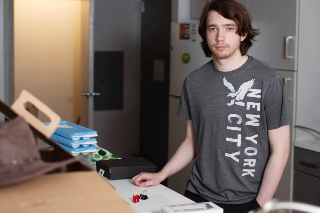 student standing in his apartment.