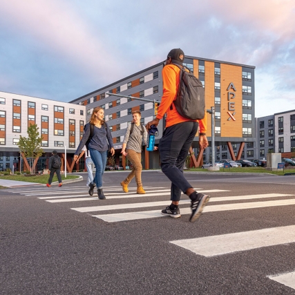 composite photo of people crossing a street in front of a new apartment complex.
