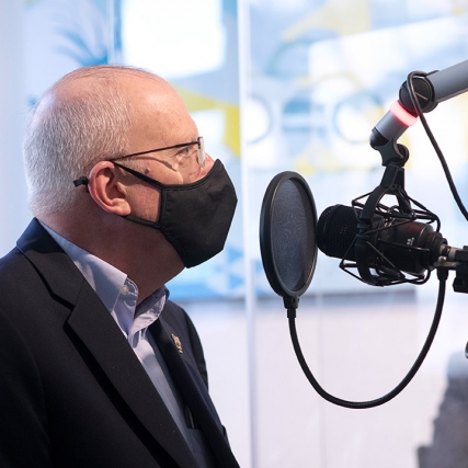 closeup of RIT President Munson talking into a radio station microphone.