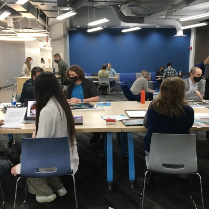 A group of students receives portfolio reviews from professional artists, including faculty.