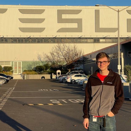 Jackson Glozer stands in front of a Tesla sign while on co-op there.