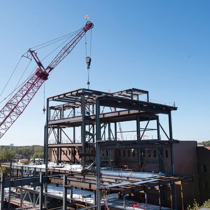crane putting support beams into place on a building construction project.