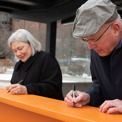 two people signing an orange support beam.