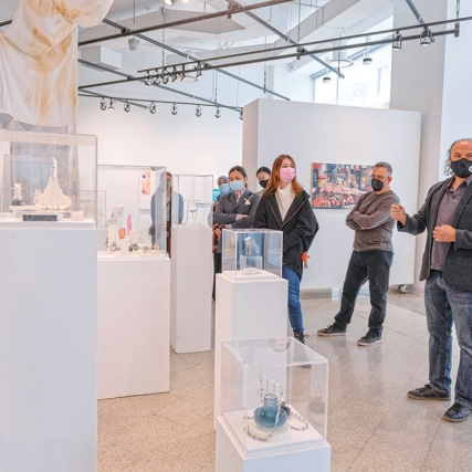 people in an art gallery looking at jewelry and prints.