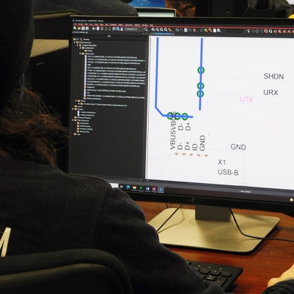student designing a printed circuit board on a computer.