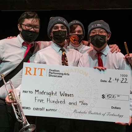 four band members holding a giant novelty check for $500.