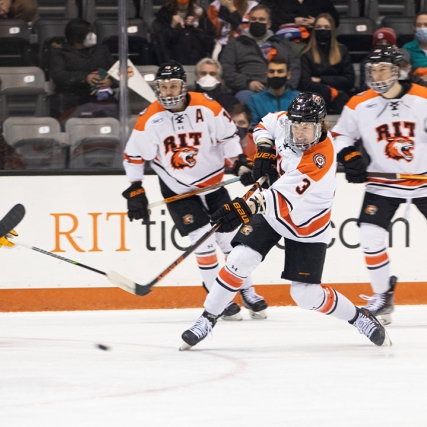 three RIT men's hockey players playing on the ice.