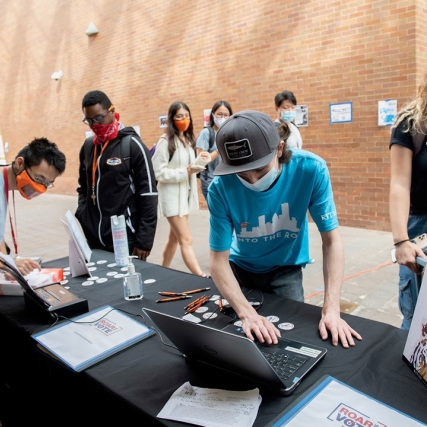 students working at a voting registration table outdoors.
