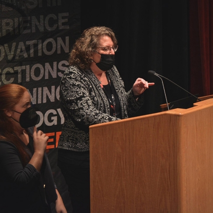 woman speaking at a podium with a sign language interpreter next to her.