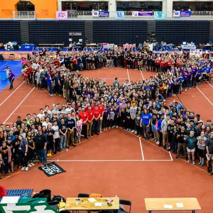 hundreds of people gathered in the shape of a ribbon.