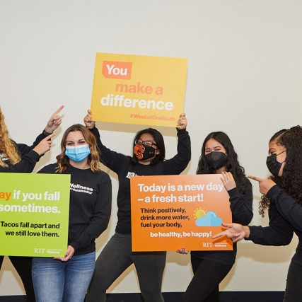 group of five students holding signs with encouraging phrases.