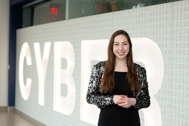 student Olivia Gallucci standing in front of a large cyber sign.
