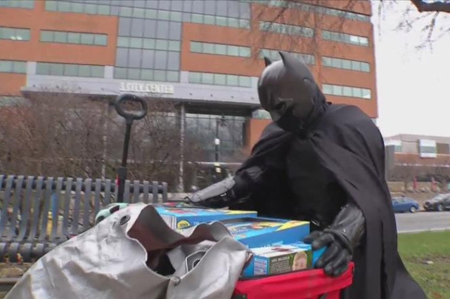 man dressed as Batman with a cart full of supplies.